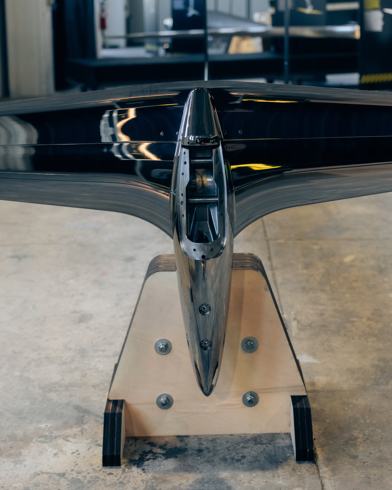 A black appendage with wide wings, resting on a wooden stand in the shipyard.